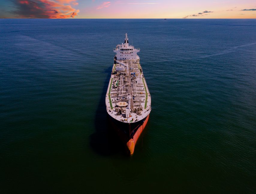 Aerial view of a large oil tanker ship on the open ocean at sunset.