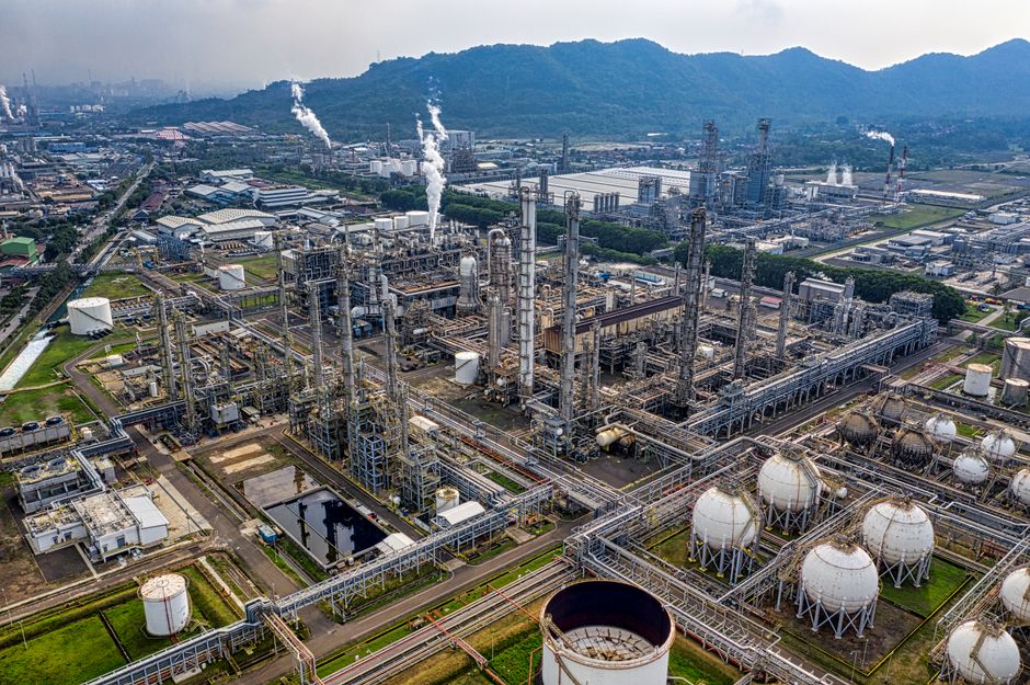 Aerial panoramic view of a large oil refinery with storage tanks, pipelines, and processing units at an industrial complex.