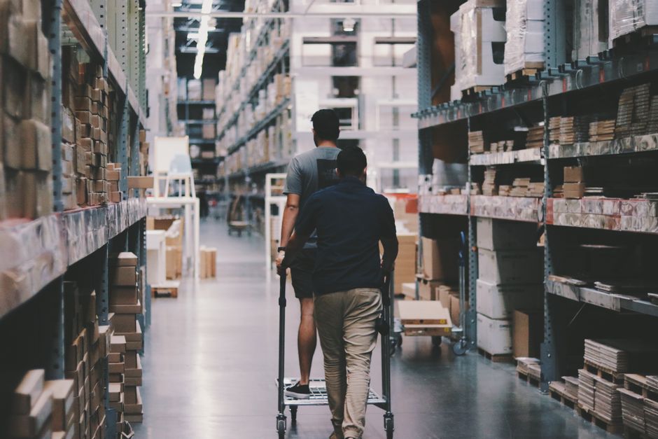 Warehouse logistics workers move inventory through a large storage facility