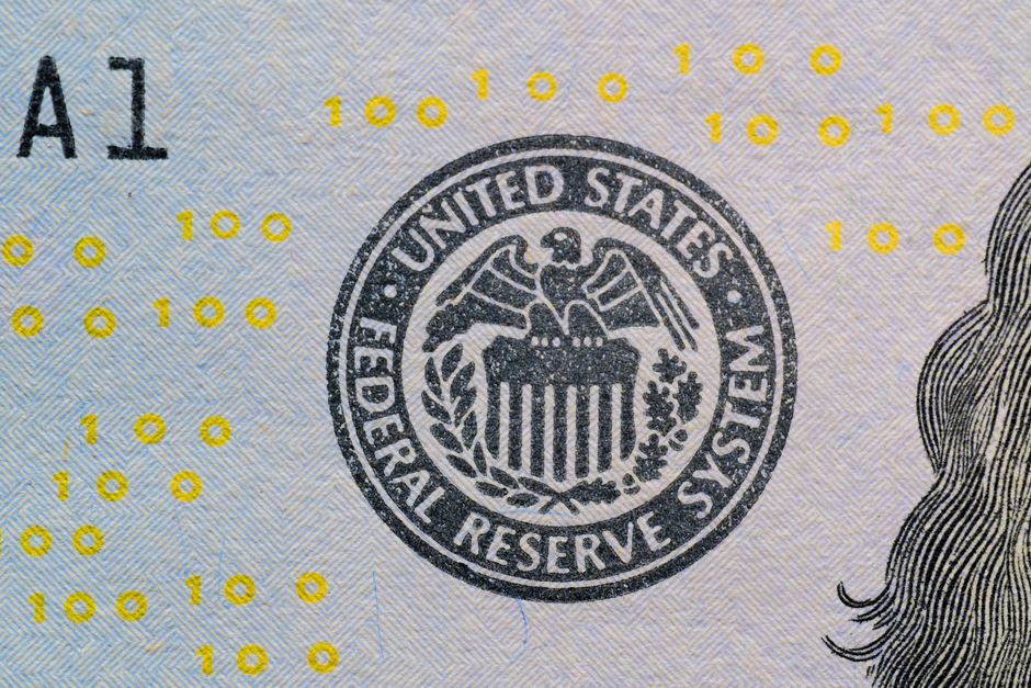 A close-up view of the Federal Reserve System seal on US currency, with yellow numerical digits visible in the background.