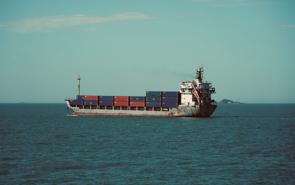 A cargo ship carrying containers sails across open water