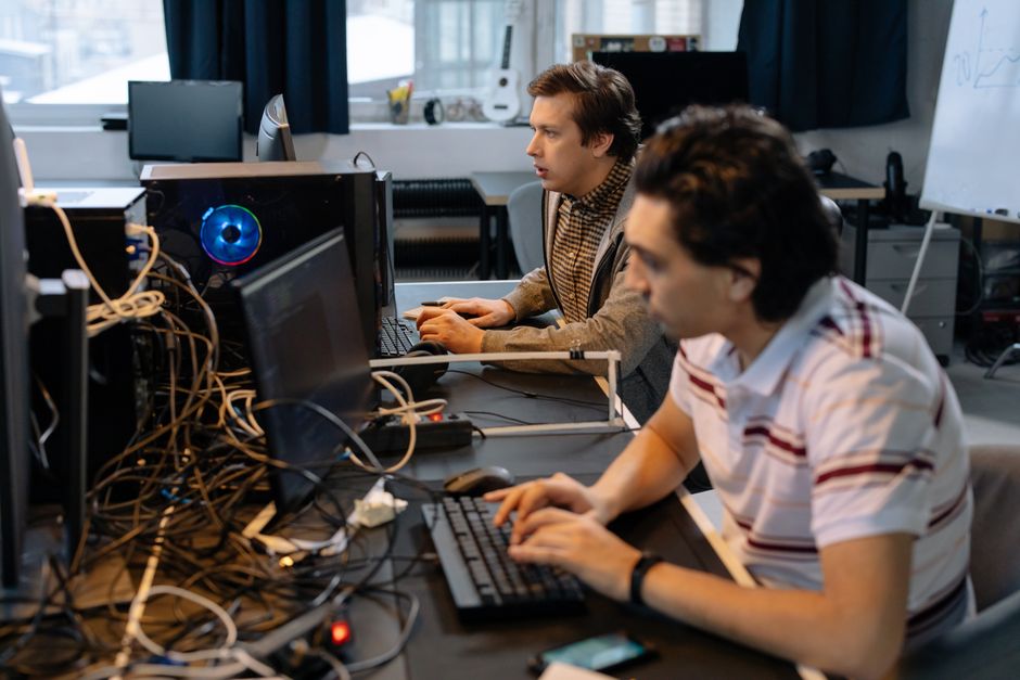 Developers collaborate at computers as enterprise software demand and AI infrastructure remain central to the market thesis.