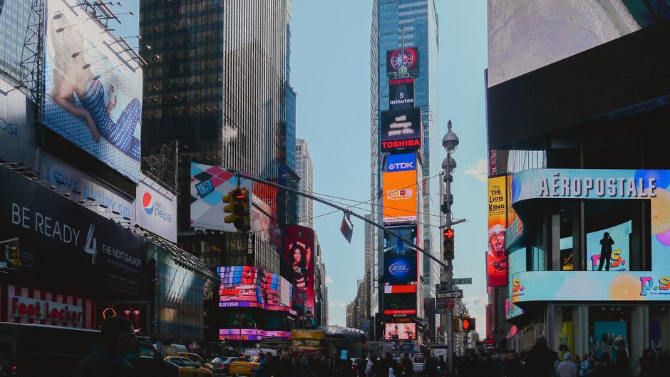 Nighttime view of illuminated commercial screens and buildings in a dense city district