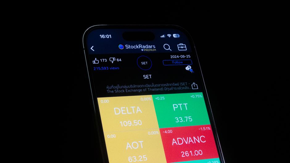A smartphone displaying stock market application data with financial metrics on a dark screen.