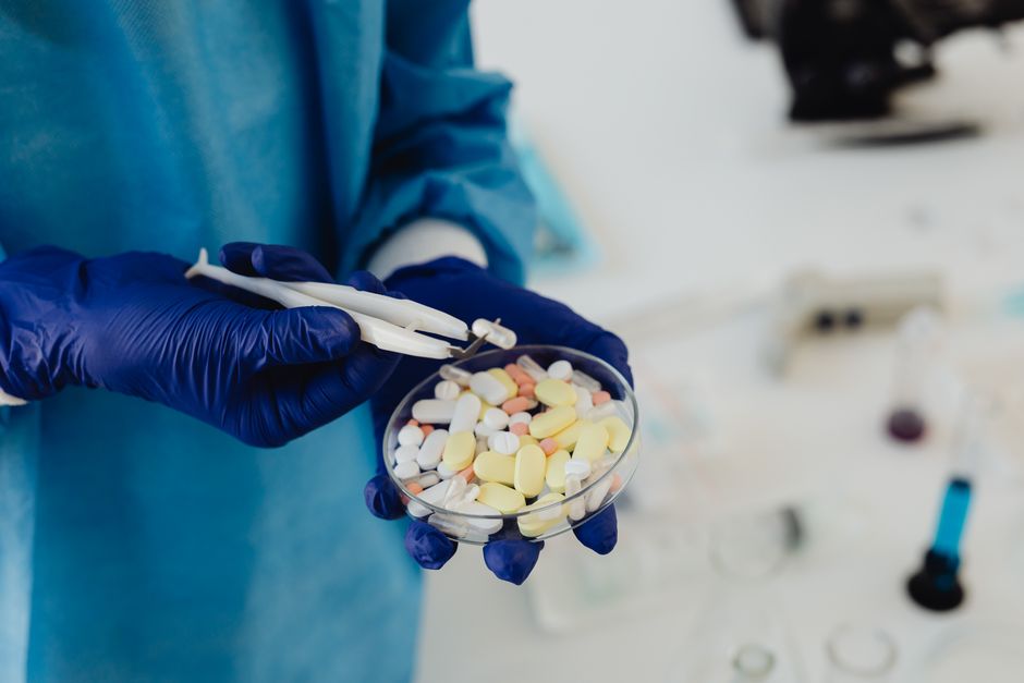 Scientist handling pills in a petri dish with tweezers