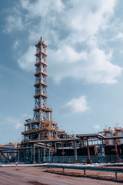 Vertical shot of an oil refinery tower against a blue sky in Trzebinia, Poland.