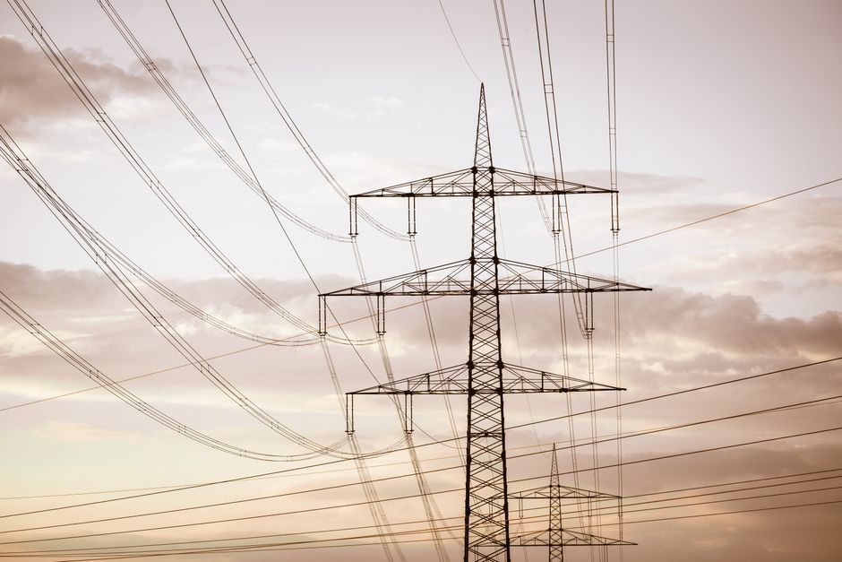 Electricity transmission pylons and high-voltage cables representing the power infrastructure required by AI data centers