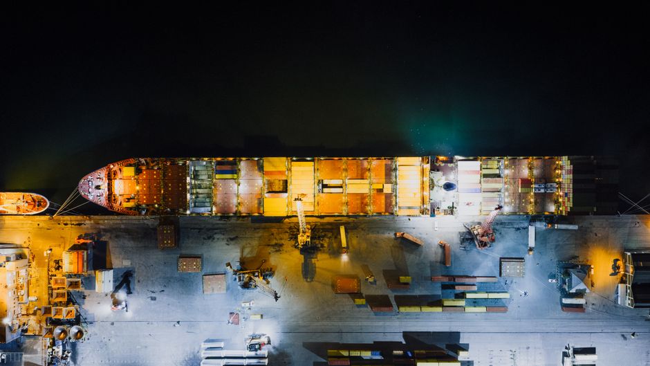 Cargo ship at a commercial harbor as geopolitical risk reaches energy and supply chains.