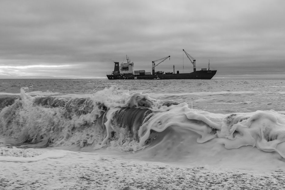 A cargo ship navigates heavy swells in open water