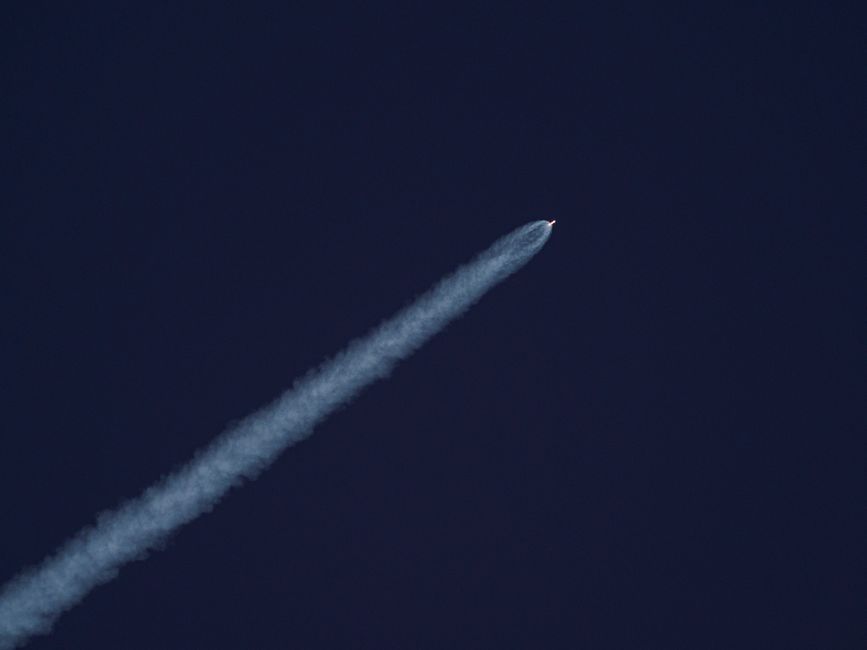 A rocket ascending into a clear sky leaving a trail of smoke, symbolizing SpaceX's record-breaking public debut and the looming pressure of its $123 billion lockup unlock.