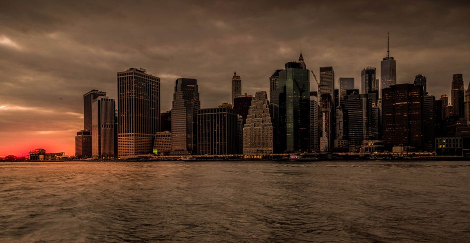 New York City skyline at sunset with golden light over the financial district, where the Dow crossed 54,000 for the first time.