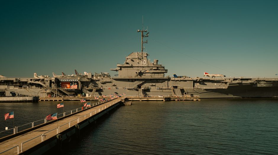 A naval warship docked at harbor, representing military power projection over critical maritime chokepoints.