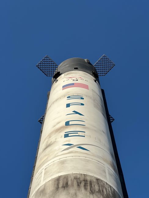 Close-up view of a SpaceX rocket against a clear blue sky, showcasing its structure and design.