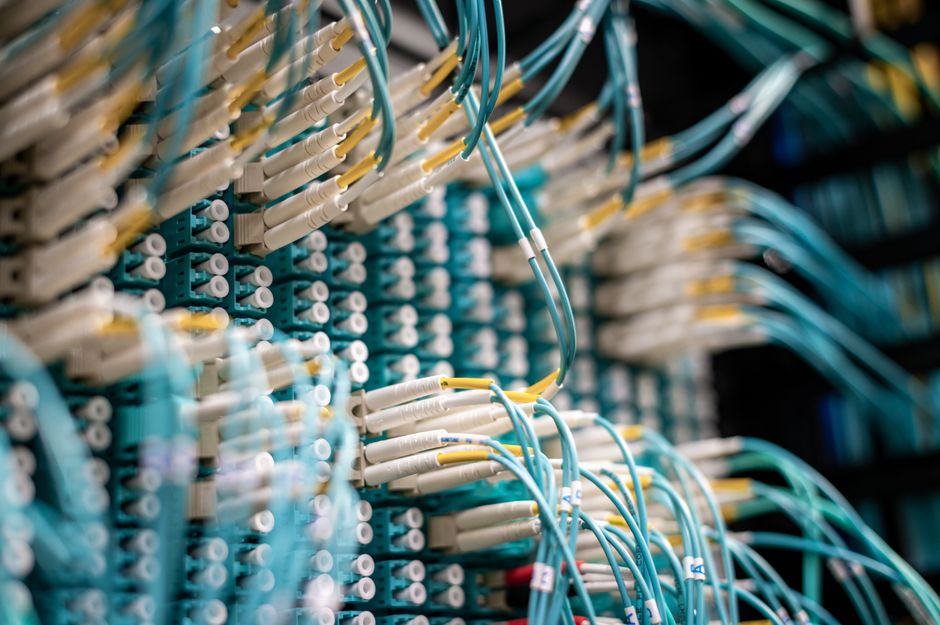 From below of fiber optic switch with sockets and connected rubber cables on blurred background.