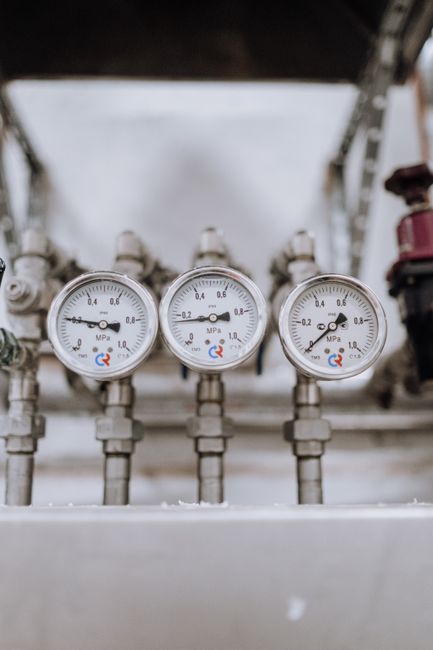 Close-up of industrial pressure gauges on pipelines, representing oil infrastructure under strain.