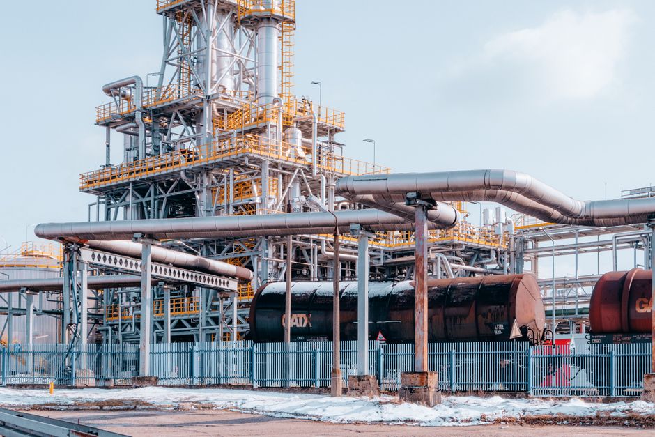 Oil refinery facility with tanker wagons under a clear sky.
