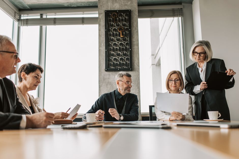 Business professionals discussing documents in a modern meeting room, representing corporate deal-making and secondary offerings.