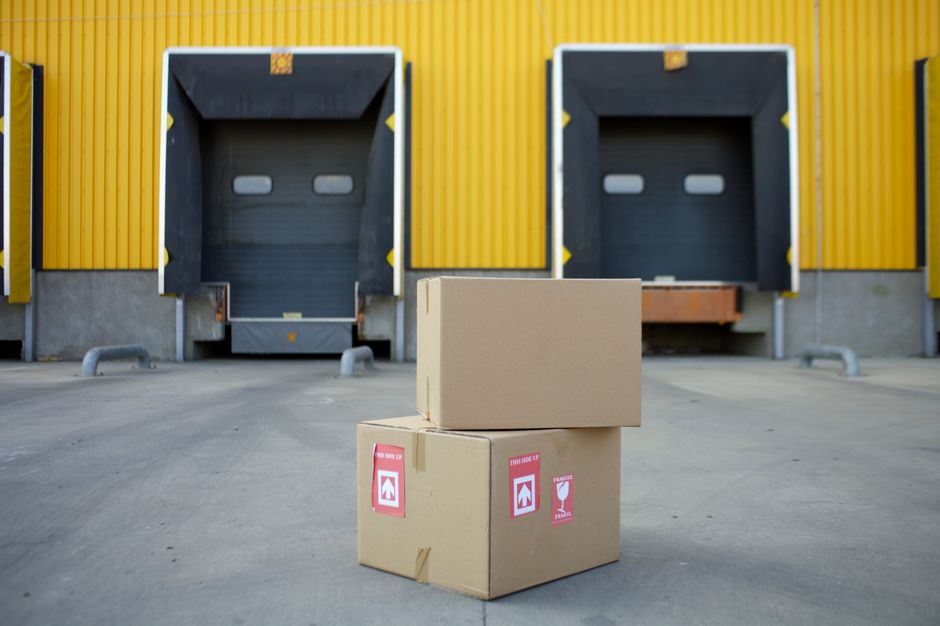 Cardboard boxes stacked at warehouse loading docks, representing Amazon's logistics and fulfillment operations.