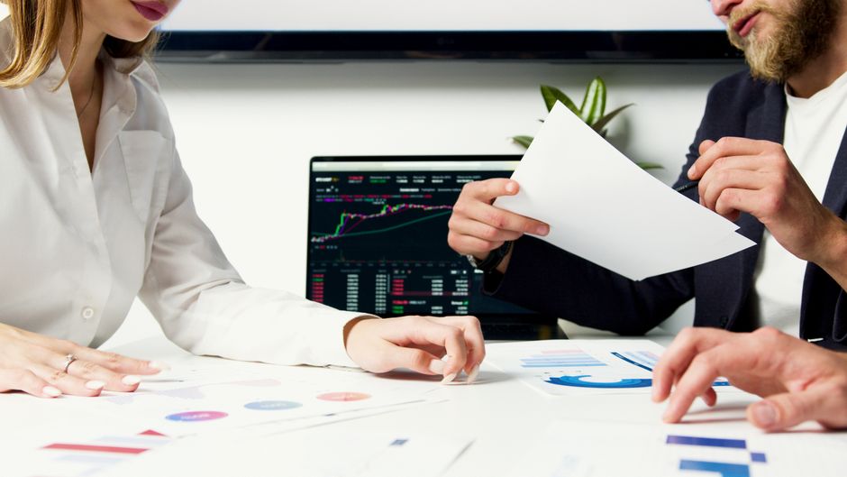 Two professionals reviewing financial data on a laptop and documents