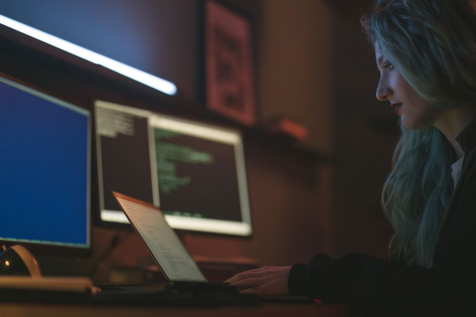 A developer working at a desk with several monitors displaying analytics and programming screens