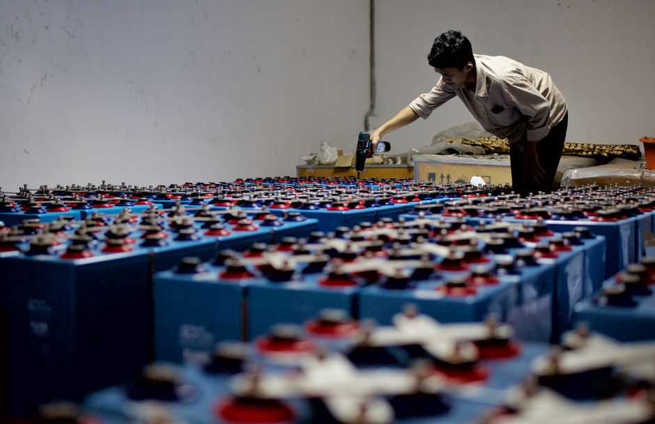 Worker inspecting industrial batteries in a manufacturing facility