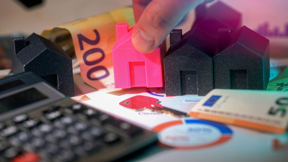 Miniature homes and financial planning materials represent housing affordability and big-ticket consumer demand