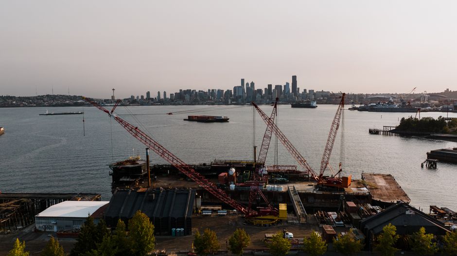 A harbor and industrial skyline represent the power, logistics and infrastructure constraints around AI data-center expansion.