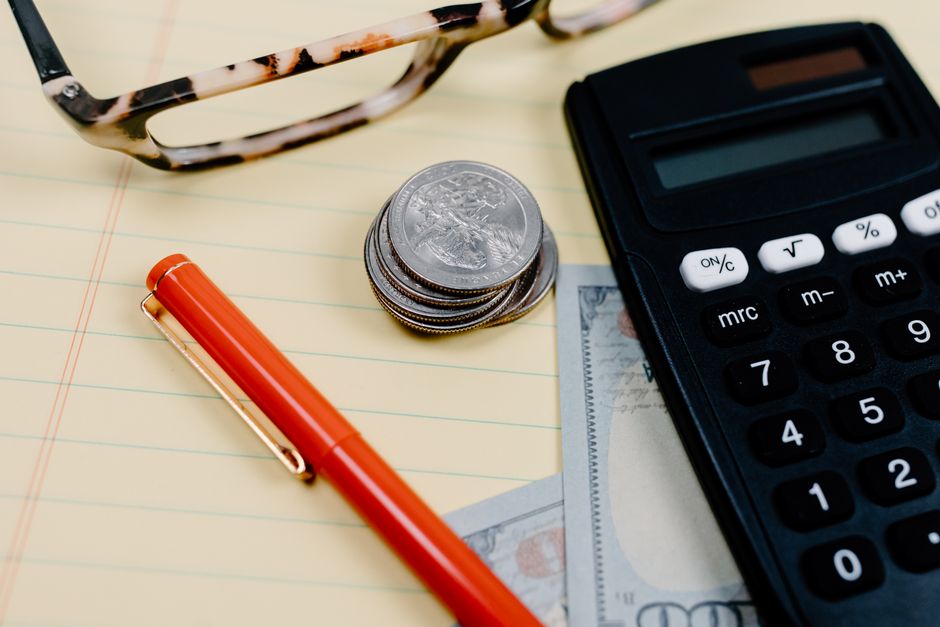 Calculator, coins, and glasses on a notepad