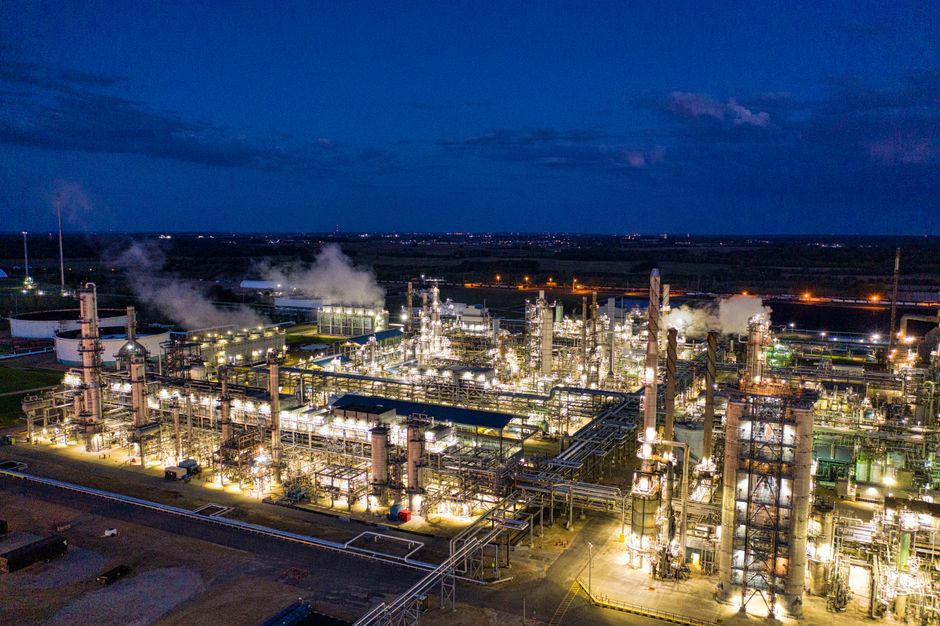 Aerial view of a well-lit crude oil refinery at night with industrial pipes and towers