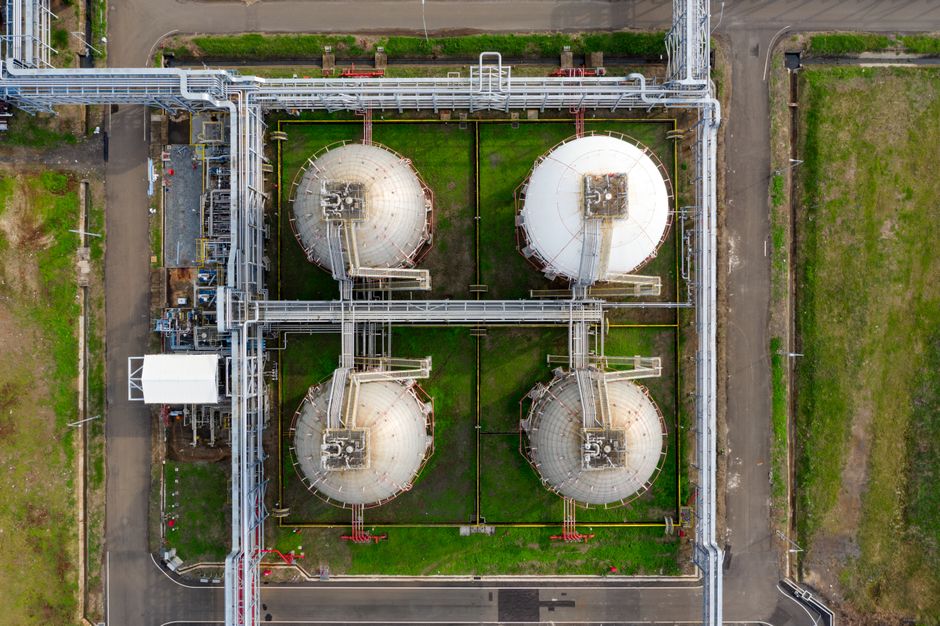 Aerial view of large industrial storage tanks and pipelines, representing the global oil storage infrastructure under strain from supply disruptions.