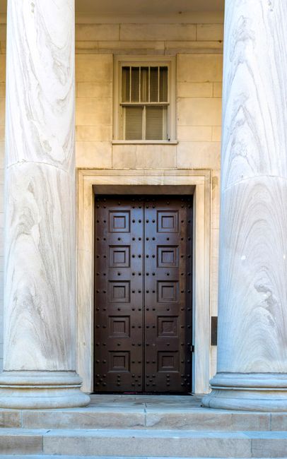 Grand wooden door framed by marble columns in a historic building facade.