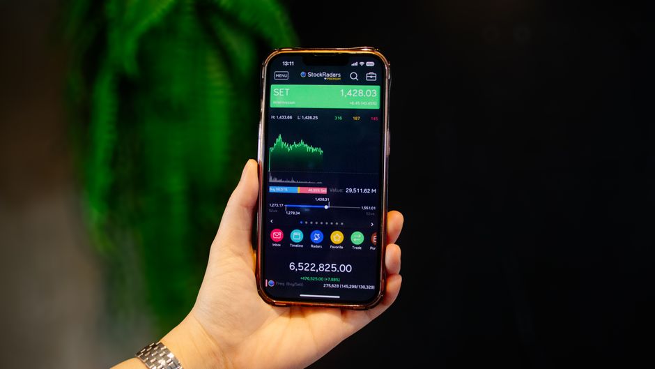 Hand holding a smartphone with a stock-market trading screen during a market rebound.