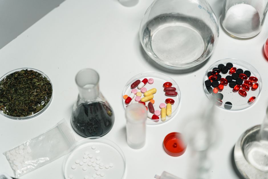 Assortment of pharmaceutical pills and chemical glassware on a white surface