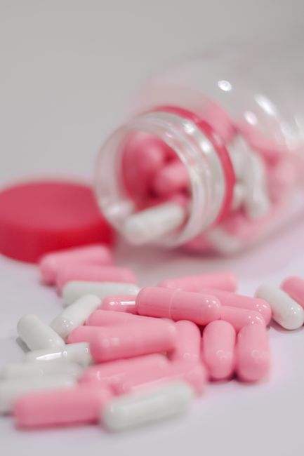 Pink and white capsules spilled from a prescription bottle
