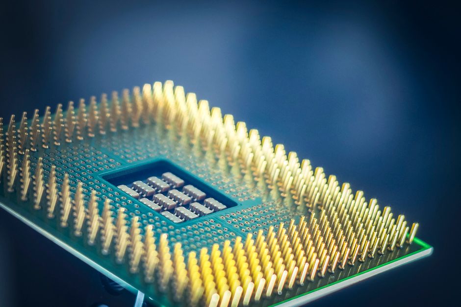 Macro shot of a computer CPU chip with gold pins against a blue background.