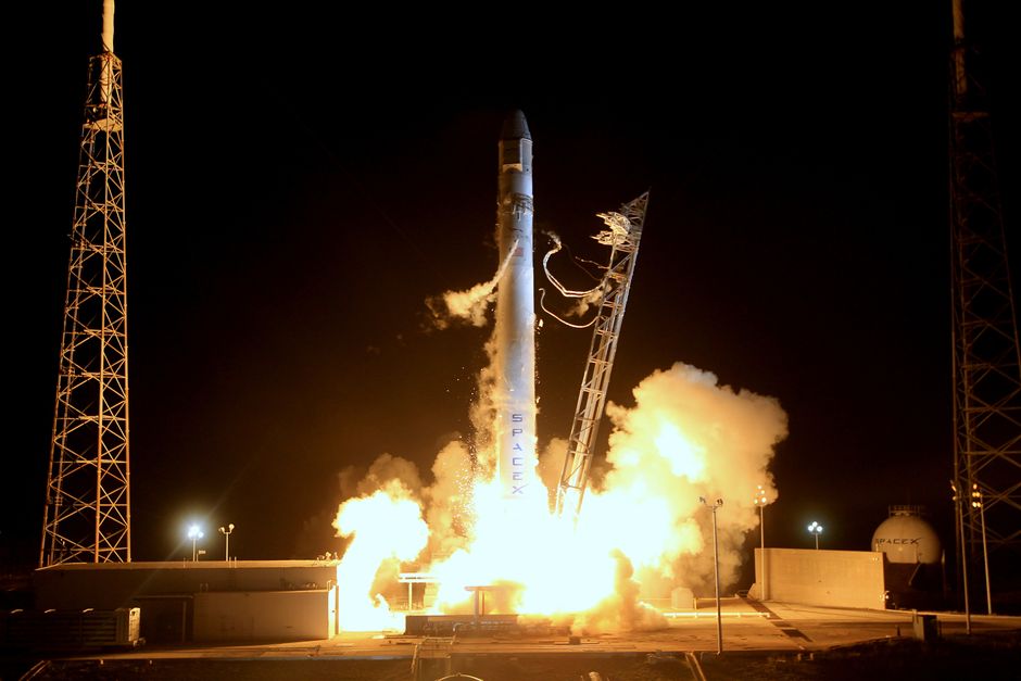 A rocket launches into a dark night sky, engines firing, beginning its ascent toward space.