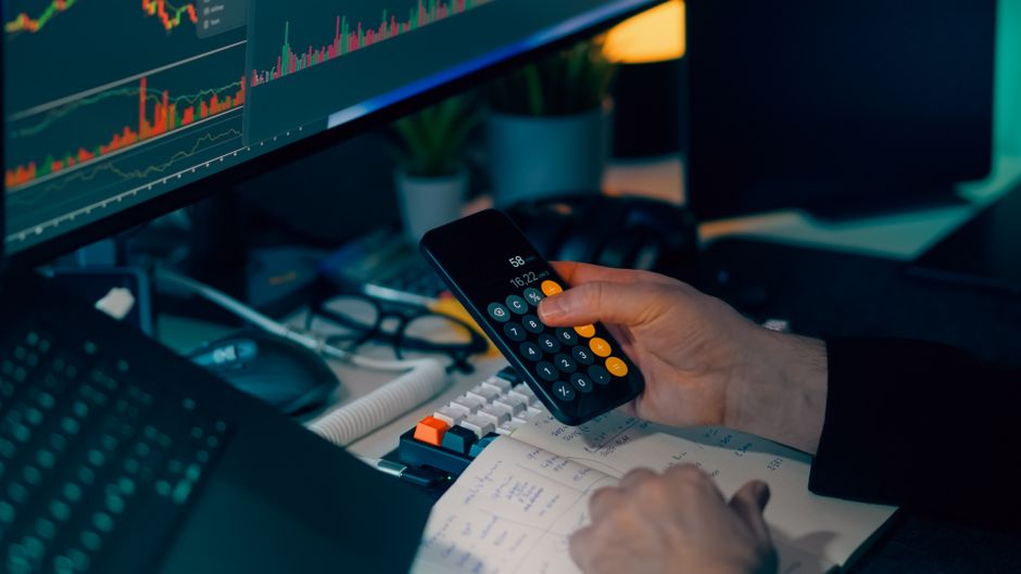 Financial analysis desk with a monitor displaying market charts, representing the market’s focus on rates and selective AI catalysts.