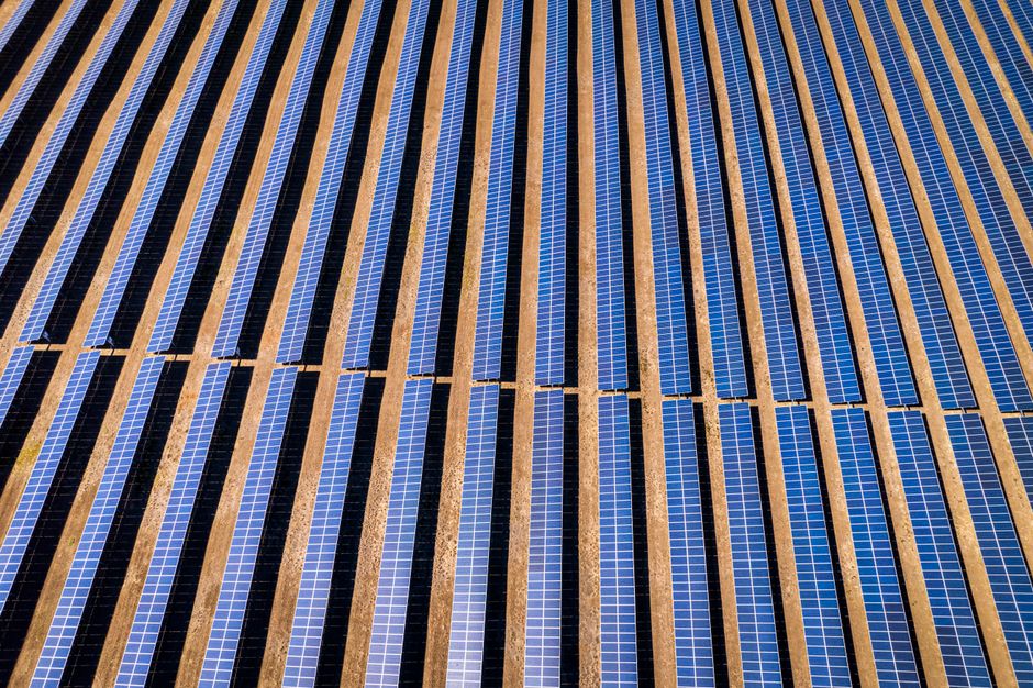 Aerial view of solar panels installed in rows across open land.