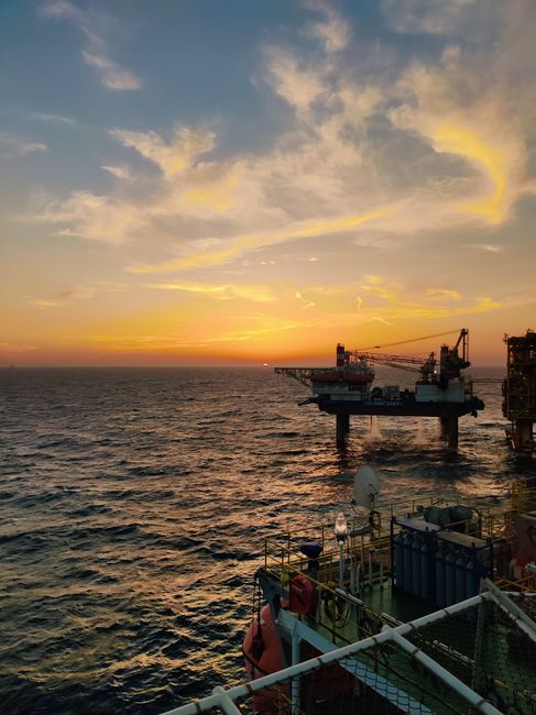 Dramatic sunset over an offshore oil rig in the Persian Gulf, showcasing industry and nature.