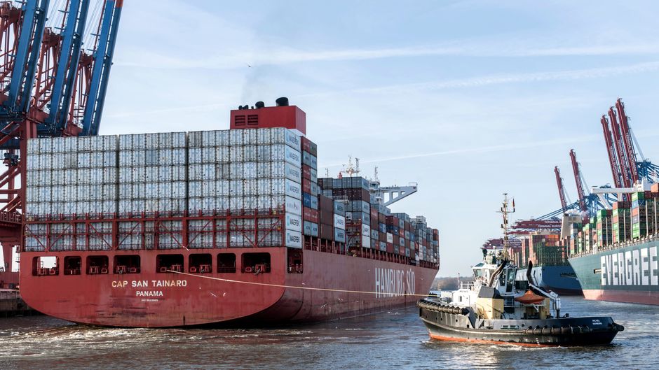 Container ships are moored at a port, emphasizing the strategic importance of maritime trade routes.