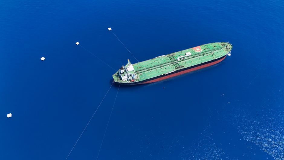 Tanker ship anchored offshore, illustrating the gap between reopening headlines and restored commercial energy flows.