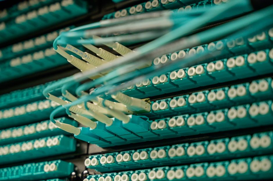 Fiber-optic cables in a data-center patch panel represent the enterprise AI and cloud infrastructure demand test.