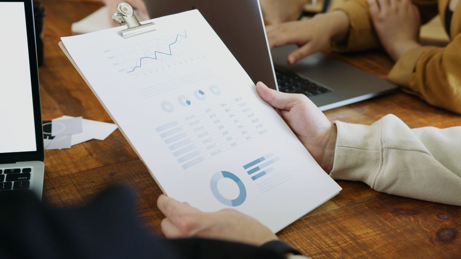 Close-up of hands holding a clipboard with charts and graphs in a business meeting