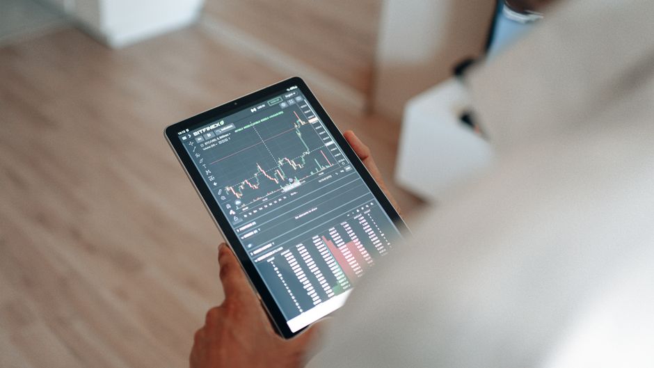A tablet shows market graphs as investors monitor liquidity and price discovery across sessions.