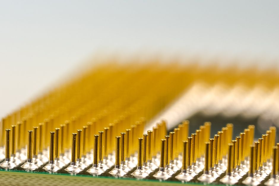 Macro photograph of a CPU microchip showing golden processor pins in sharp detail.