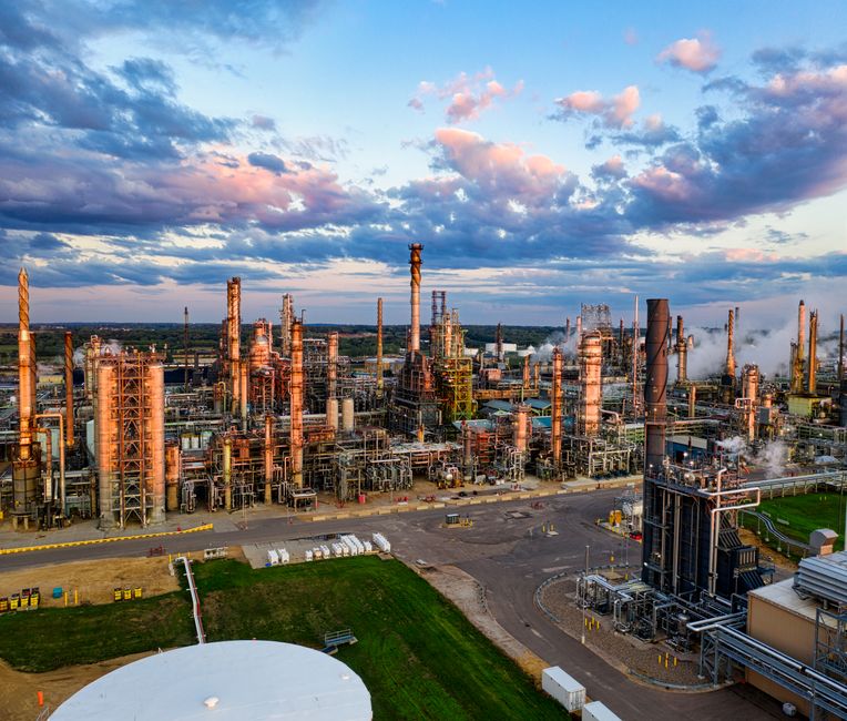 Oil refinery industrial complex at dusk, representing the energy infrastructure under supply-chain pressure from the Hormuz standoff.