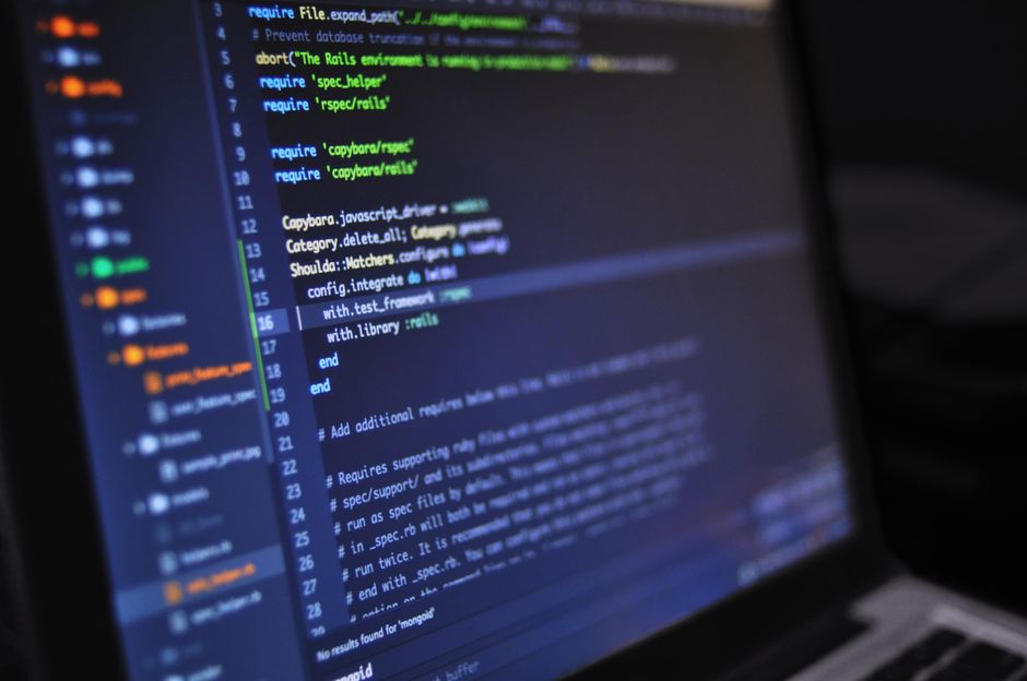 Close-up of a computer screen displaying programming code in a dark environment, representing the electronic infrastructure behind algorithmic equity trading.