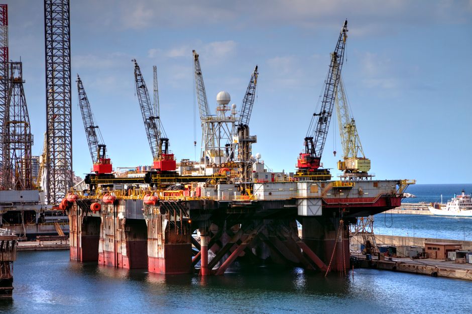 Offshore oil platform with cranes in a harbor, capturing industrial and marine infrastructure.