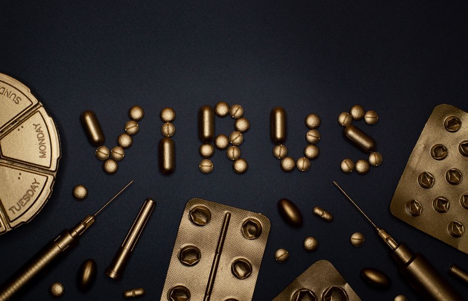 Syringes and gold pills arranged on a dark blue surface, representing biologic drug development.