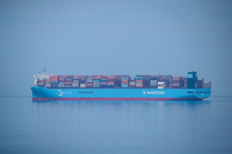 A large container ship loaded with cargo sailing across a calm open sea, emblematic of a global shipping lane.